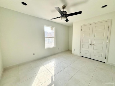 Unfurnished bedroom with light tile patterned flooring, a closet, and a ceiling fan
