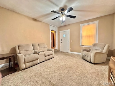 Carpeted living room featuring baseboards and a ceiling fan