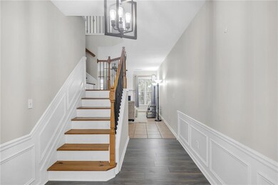Staircase with a decorative wall, a chandelier, wainscoting, and wood finished floors