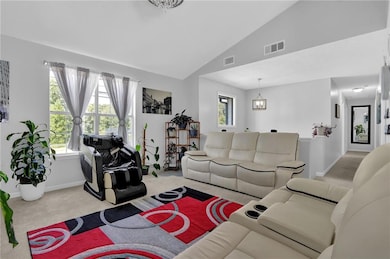 Living room with carpet flooring, a chandelier, and high vaulted ceiling