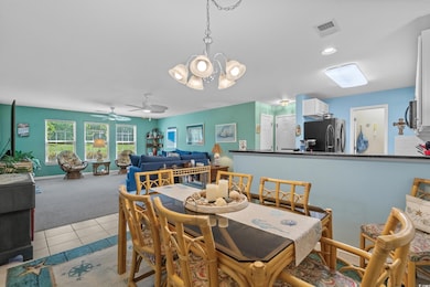 Dining space with light carpet, a chandelier, light tile patterned flooring, a ceiling fan, and recessed lighting