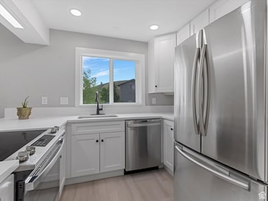 Kitchen featuring appliances with stainless steel finishes, white cabinets, recessed lighting, and light wood-style flooring