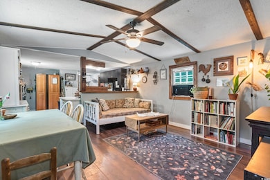 Living area with a textured ceiling, ceiling fan, and wood finished floors