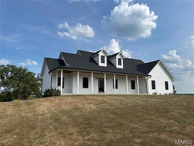 View of front of house with covered porch, a shingled roof, and a front lawn