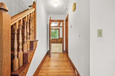 Hall featuring light wood-style flooring, ornamental molding, and baseboards
