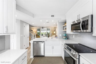New steel appliances, white cabinetry, and quartz