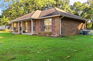 View of side of home with brick siding, a porch, and roof with shingles