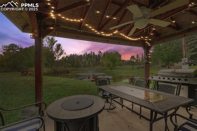 Patio terrace at dusk with a water view, outdoor dining space, a yard, a ceiling fan, and a patio