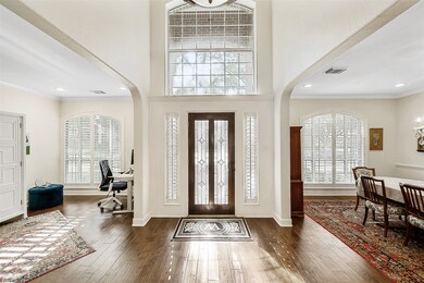 The entry of the home is warm and inviting, featuring a beautifully etched glass front door that sets a welcoming tone. Hard wood floors, which flow seamlessly throughout the house, add a touch of elegance and warmth. The tall ceiling in the entryway enhances the openness of the space, creating an airy and spacious feel.