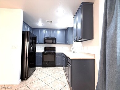 Kitchen with black appliances, light tile patterne