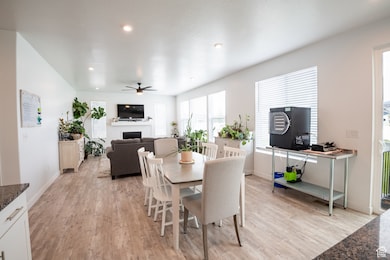 Dining space with light wood-style floors, recessed lighting, a fireplace, and a ceiling fan