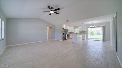 Unfurnished living room with ceiling fan, a chandelier, light wood-style flooring, and vaulted ceiling