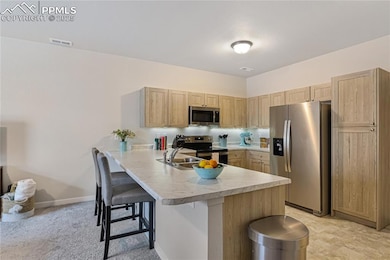 KITCHEN EQUIPPED WITH STAINLESS STEEL APPLIANCES, SOFT-CLOSE CABINETS, AND A GENEROUS BREAKFAST BAR AND UNDER-CABINET LIGHTING