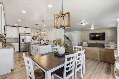 Dining room featuring a chandelier, light wood-style flooring, recessed lighting, and stairway
