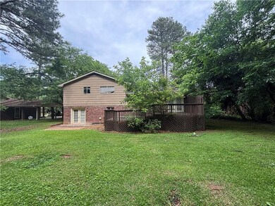 Back of house featuring a deck, a lawn, french doors, and brick siding