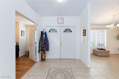 Foyer entrance featuring a chandelier and light ti