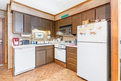 Kitchen featuring white appliances, crown molding,