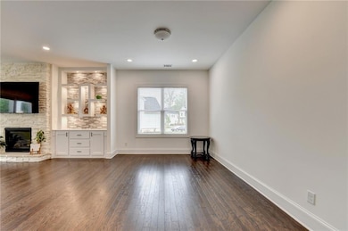 Unfurnished living room with baseboards, dark wood