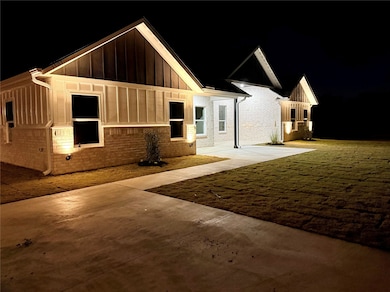 View of front facade with brick siding, board and batten siding, and a lawn