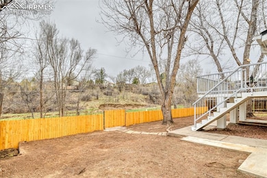 View of yard with a gate, fence, and stairway