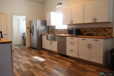 Kitchen featuring butcher block countertops, white cabinetry, tasteful backsplash, and stainless steel appliances