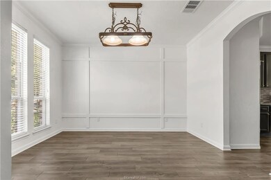 Unfurnished dining area with ornamental molding, arched walkways, and dark wood-style flooring