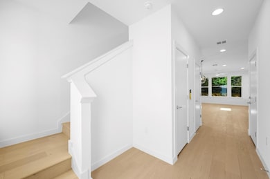 Hall with visible vents, baseboards, light wood f