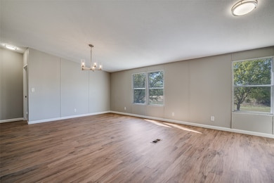 Spare room featuring wood finished floors and a chandelier