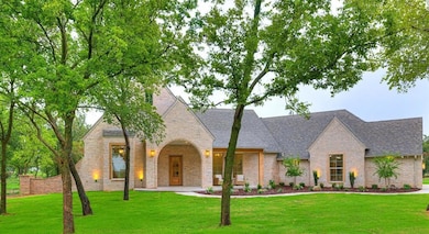 View of front facade with a front yard, brick siding, covered porch, and a shingled roof
