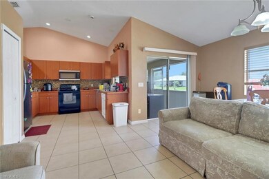 Kitchen featuring appliances with stainless steel finishes, vaulted ceiling, open floor plan, decorative backsplash, and light tile patterned flooring