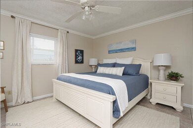 Bedroom with a textured ceiling, ornamental molding, a ceiling fan, and light tile patterned flooring