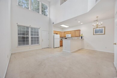 Unfurnished living room featuring a chandelier, light carpet, a high ceiling, and recessed lighting