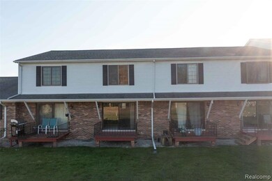 Back of property with a deck, brick siding, and a lawn