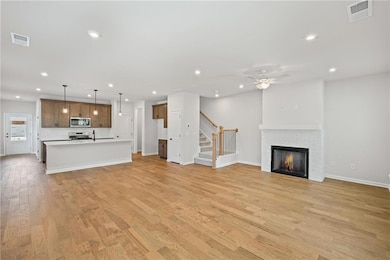 Unfurnished living room featuring a fireplace, light wood-style floors, recessed lighting, a ceiling fan, and stairs