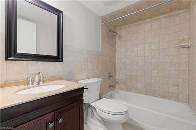 Bathroom featuring tile walls, tub / shower combination, and vanity