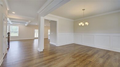 Spare room with crown molding, wood finished floors, a wainscoted wall, a chandelier, and a decorative wall