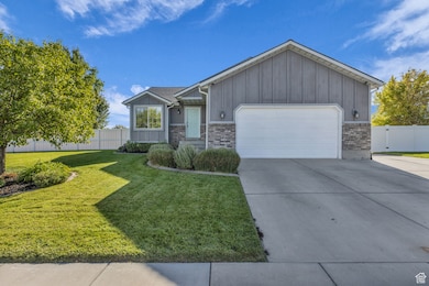 View of front of home featuring board and batten siding, an attached garage, driveway, brick siding, and a gate