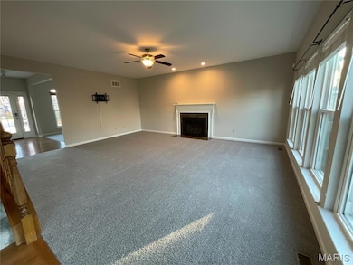 Unfurnished living room featuring healthy amount of natural light, recessed lighting, a ceiling fan, a fireplace with flush hearth, and carpet