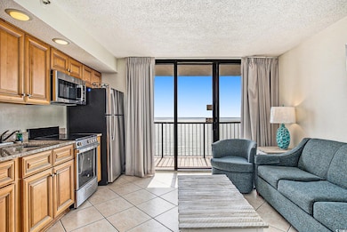 Kitchen featuring brown cabinetry, a wall of windows, stainless steel appliances, a water view, and dark stone counters