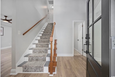 Entrance foyer featuring light wood-style floors, a ceiling fan, and stairs