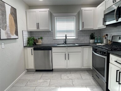 Kitchen featuring white cabinetry, sink, backsplash, and stainless steel appliances