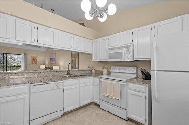 Kitchen featuring white appliances, lofted ceiling