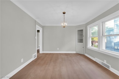 Unfurnished dining area featuring light wood-style floors and a chandelier