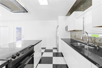 Kitchen featuring dark stone counters, stainless steel appliances, sink, white cabinetry, and plenty of natural light