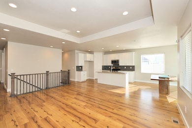 Unfurnished living room with recessed lighting, light wood finished floors, and a raised ceiling