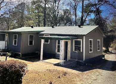 View of front of home with a metal roof and view of wooded area