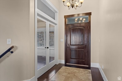 Entrance foyer featuring dark wood-type flooring, a chandelier, and french doors