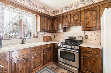 Kitchen featuring white fridge, stainless steel gas range, dark tile floors, sink, and dark brown cabinets