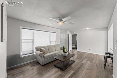 Living area with a textured ceiling, wood finished floors, and ceiling fan
