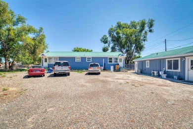 View of front facade with a metal roof, gravel driveway, and board and batten siding